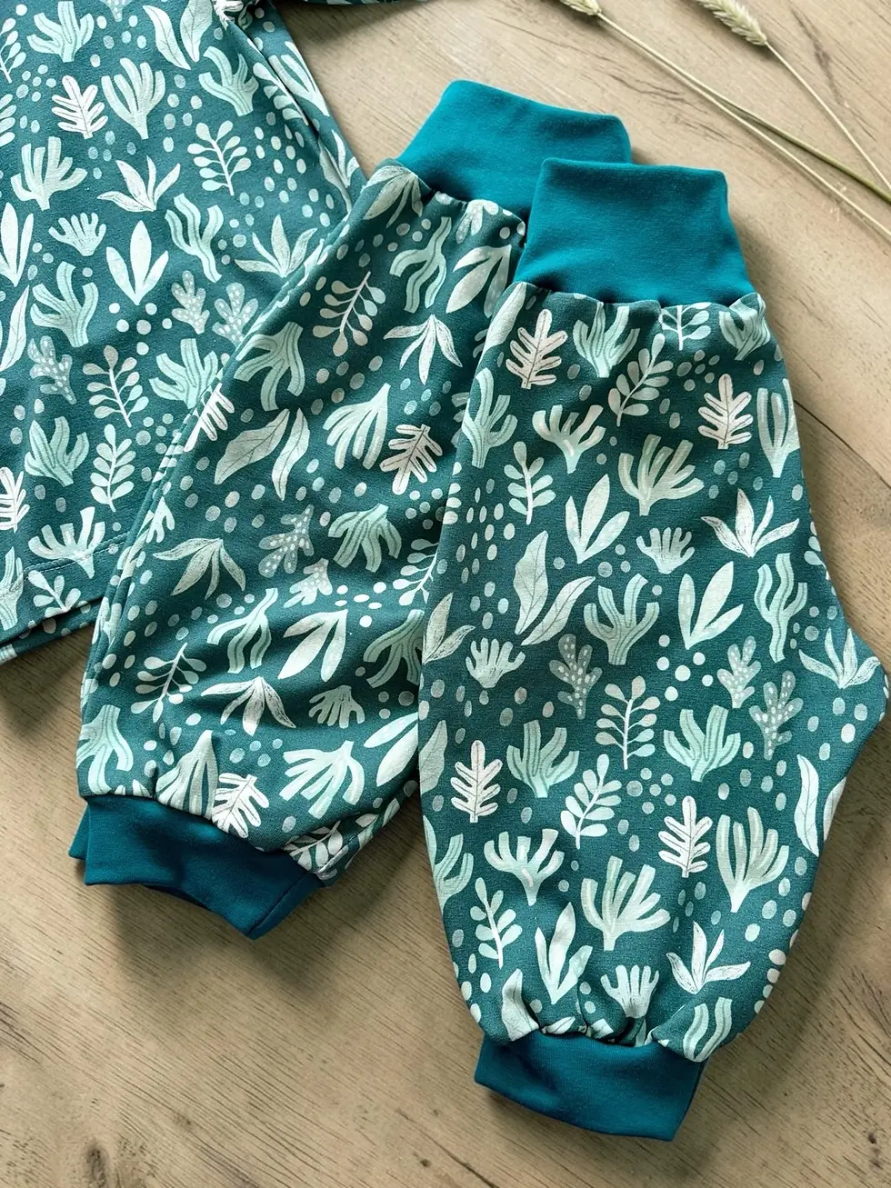 Miniaturbild: Detailaufnahme von Shirt und Hose „Küstenwiese“. Handgemachte Kindermode mit botanischem Muster im nordischen Stil.