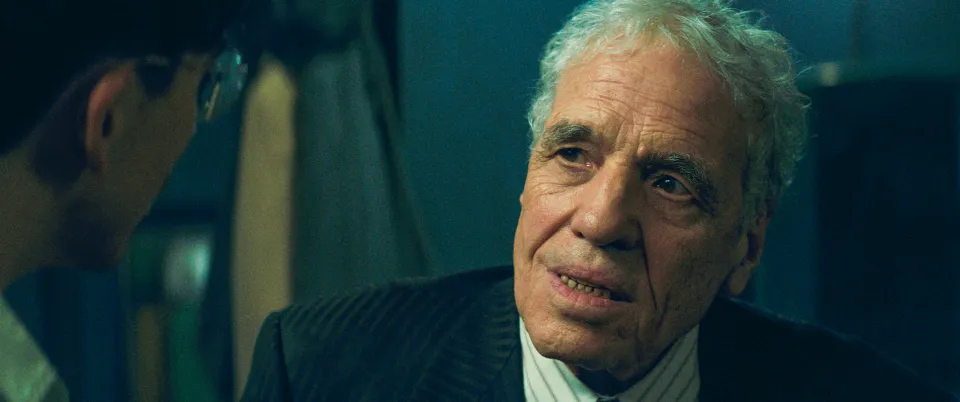 An old man with rough facial features and grey hair is gazing thoughtfully.