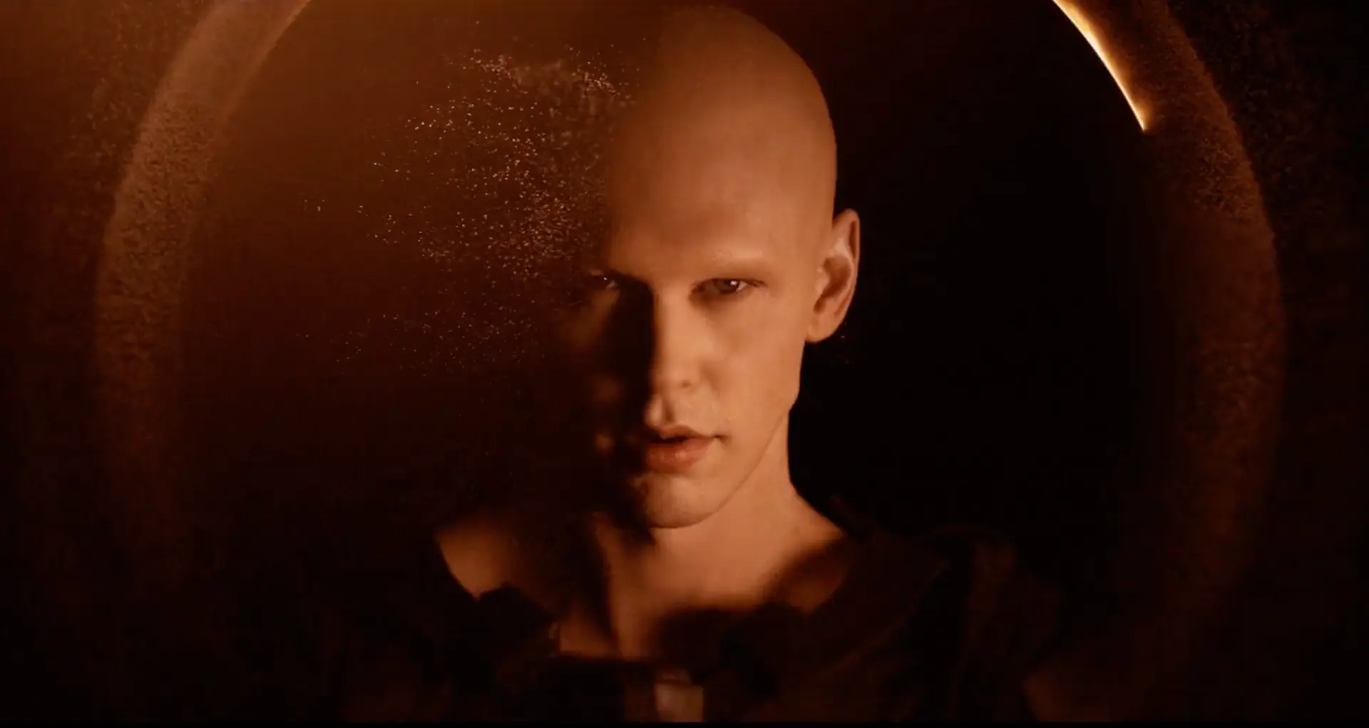 a bald man's head and shoulders facing the viewer  and staring intensely