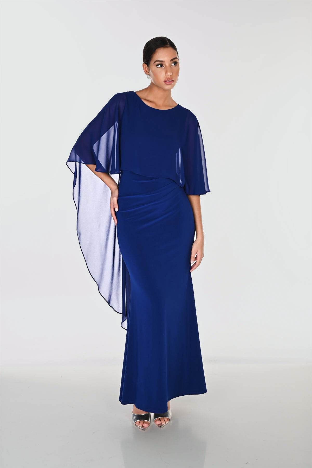 Elegant marineblå maxikjole fra Frank Lyman med flatterende rynkedetaljer, feminine volangermer og en eksklusiv smykkedetalj.