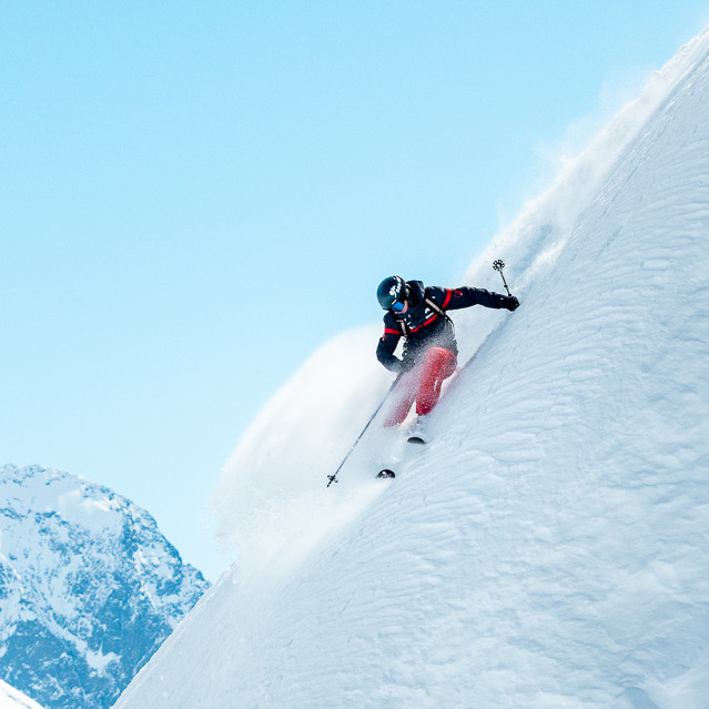 Skier skiing down a steep off-piste powder slope