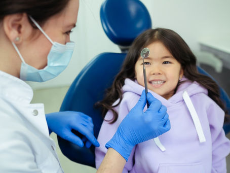 Pediatric dentist showing dental tools to a child.