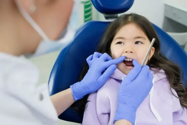 Pediatrci dentist checking child’s gum