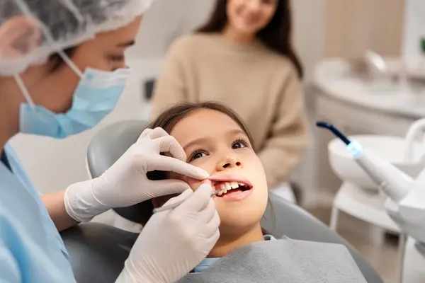 Pediatric dentist repairing a child’s chipped tooth with tooth-colored composite