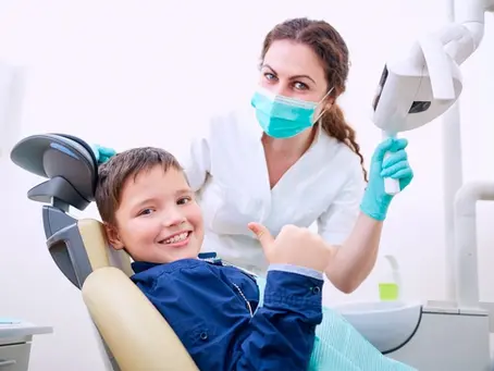 Smiling child reassures with a thumbs up after routine dental care.