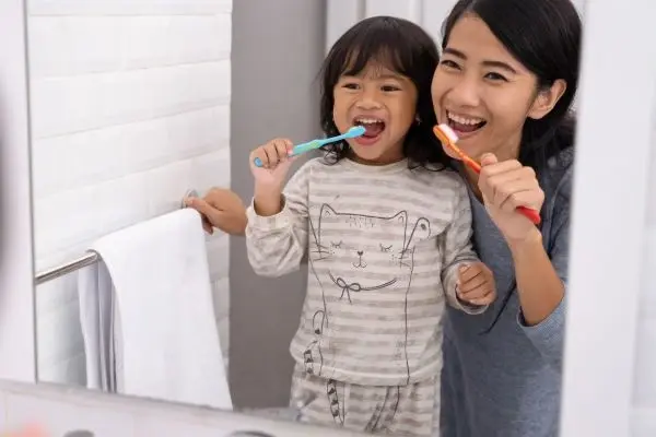Mother guiding child on brushing teeth