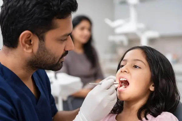 Pediatric dentist examining gum swelling near a child's baby tooth