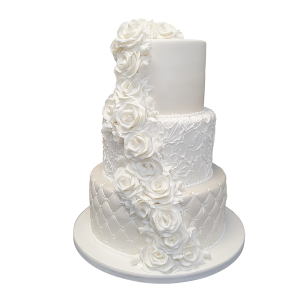 Three-tier white wedding cake with sugar paste roses, lace detailing, and quilted pattern.