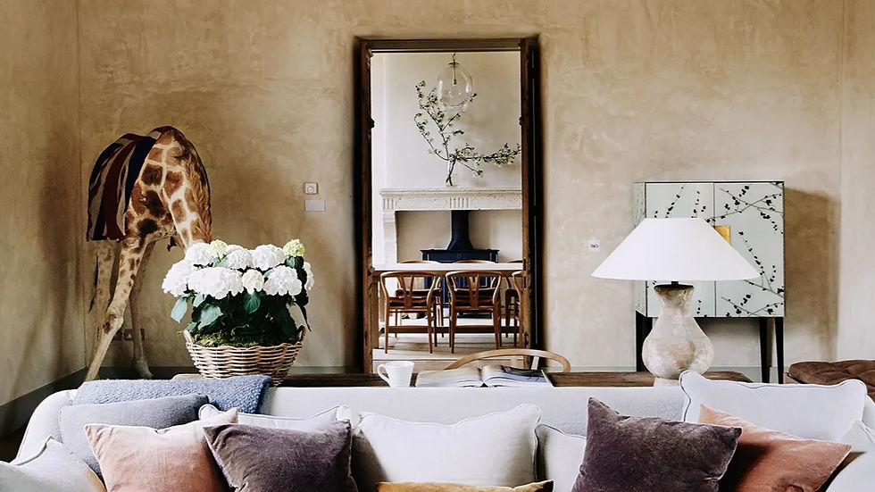 Cozy room with a giraffe sculpture, white flowers in a basket, and a patterned cabinet. Neutral tones and a view into a dining area.