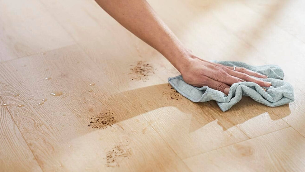 Hand wiping vinyl wooden floor with cloth, cleaning dirt and water droplets. Bright setting, light wood texture, focused on cleanliness.