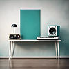 white table with nothing on it up against a blank wall that is teal with music and albums