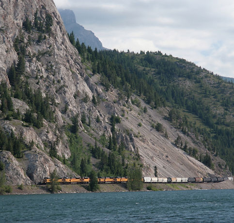 A freight train travels between a mountain and lake in Alberta Southwest, reflecting the region's strong transportation links