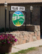 A painted and carved wooden sign reads"Hill Spring — Prairie to Peak Perfection."