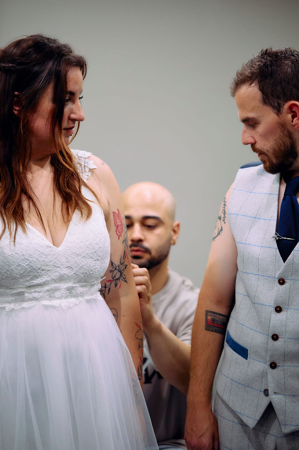 Bride and groom in wedding attire getting matching fingerprint heart tattoos at Creato Tattoo Studio in Liverpool by an expert tattoo artist.”