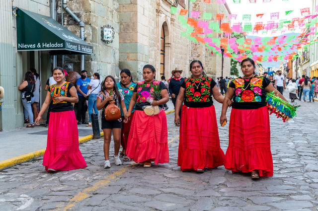 Women in colorful traditional clothes at a Mexican street festival in Oaxaca.