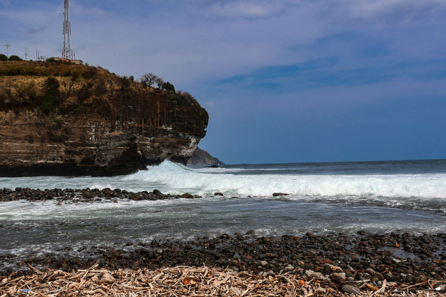 Waves crash against a rocky shore and cliff.