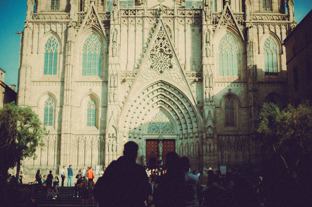Tourists gather in front of a stunning Gothic cathedral facade in Barcelona, Spain.