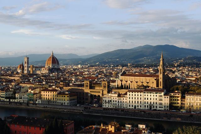 Panoramic view of florence cityscape with mountains behind.