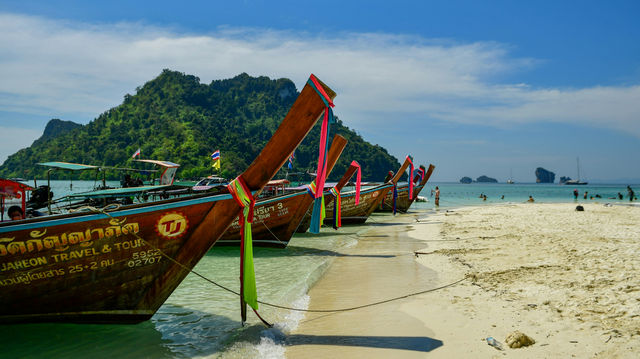 A dramatic limestone cliff rises from the deep blue sea at Poda Island, Thailand, showcasing the raw natural beauty and iconic seascape of this tropical destination.