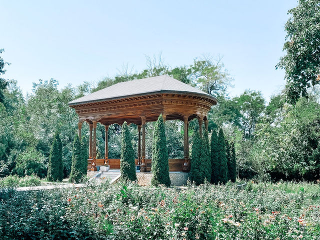 A wooden pavilion surrounded by greenery in a summer garden in Dushanbe, Tajikistan.