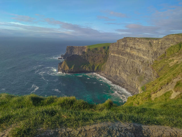 The Cliffs of Moher are sea cliffs on the west coast of Ireland in County Clare, known for their dramatic drops into the Atlantic Ocean and panoramic views. They stretch for about 14 kilometers and ar