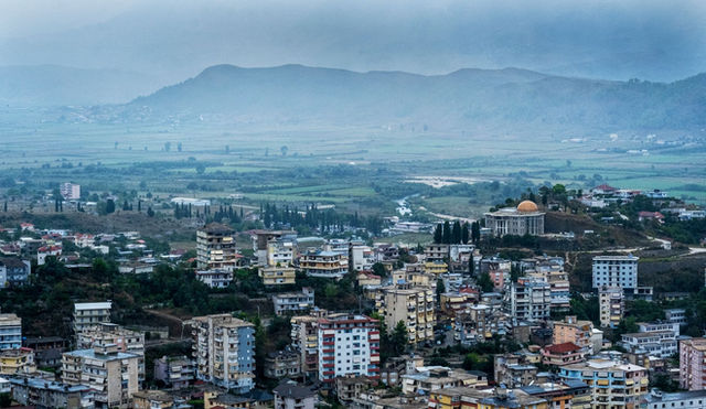 Vibrant cityscape of Albania with lush greenery and mountainous backdrop.
