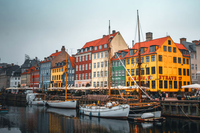 Colorful buildings line a canal with boats in copenhagen.
