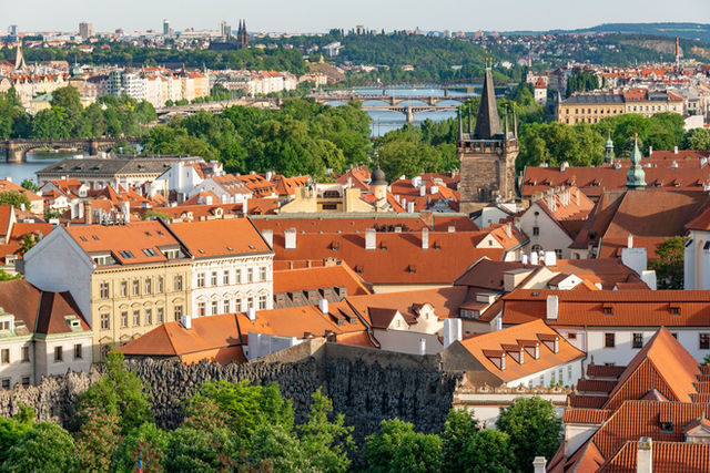 Stunning aerial view of Prague cityscape, featuring red roofs, Gothic architecture, and the Vltava River.