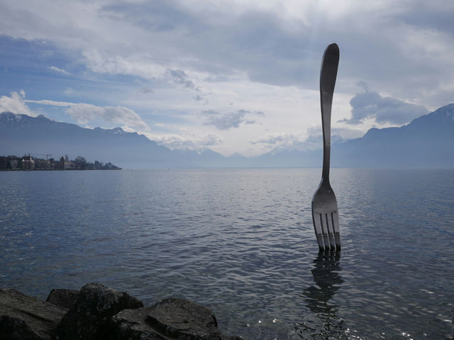 Giant fork sculpture in Lake Geneva with Swiss Alps in the background