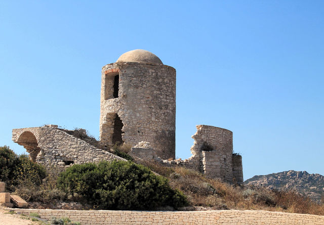 Stone ruins of an ancient castle under a clear blue sky in Corsica, France.