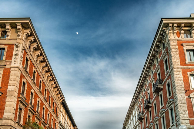 Symmetrical view of historic buildings under a clear sky in Milan, Italy.