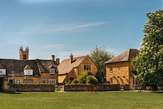 A picturesque view of traditional Cotswolds stone houses under a clear blue sky.