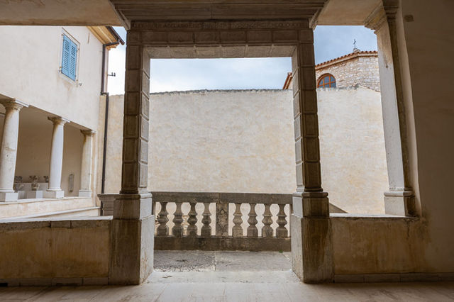 Explore the serene historical architecture of Euphrasian Basilica's cloister in Poreč, Croatia.