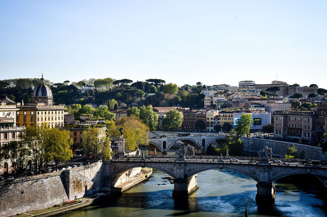 Beautiful view of Ponte Sant'Angelo spanning the Tiber River in Rome, Italy under a clear sky.