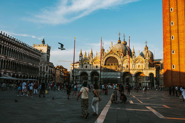 Tourists enjoying the vibrant atmosphere around St. Mark's Basilica in Venice during sunset.