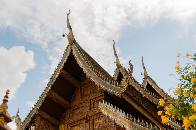 Beautifully ornate temple roof with traditional Thai architecture in Chiang Mai under a clear blue sky.