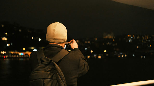A man is taking a picture of a city at night