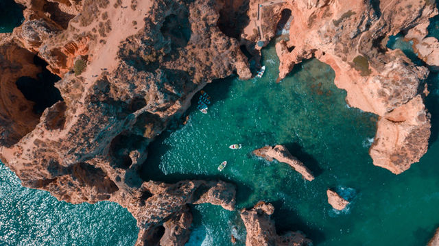 A breathtaking aerial view of the Algarve coastline in Portugal with rugged rock formations and clear blue sea.