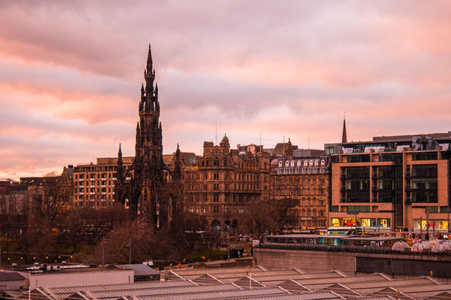 View of Scott Monument and Edinburgh skyline at sunset, offering a picturesque travel destination.