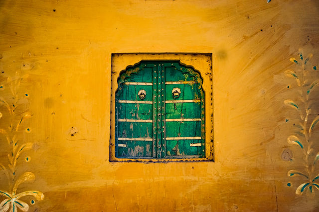 A green door set into an ochre wall