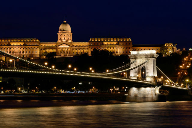 Illuminated castle and bridge over river at night