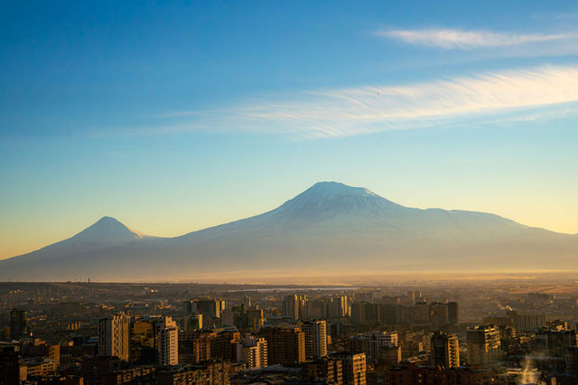 Majestic mountains rise above a city skyline at dawn.