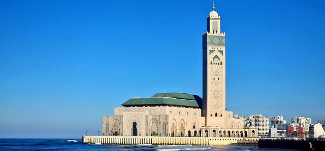The majestic Hassan II Mosque in Casablanca with a vibrant blue sky background.
