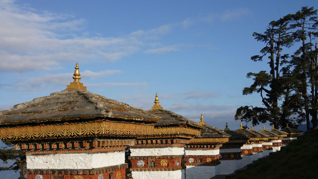 Traditional bhutanese architecture with ornate roofs against blue sky.