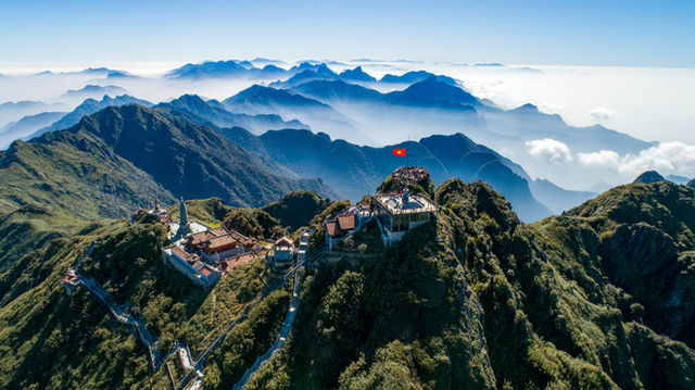 Mountain peak with buildings and flag under clear sky