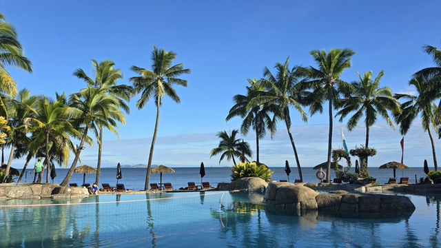 Palms over a pool blue with tropical ocean, a perfect travel destination -Fiji