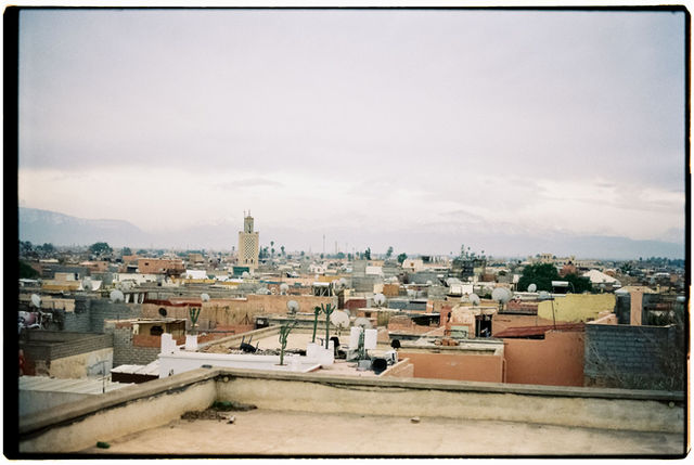 Explore the rustic rooftops of Marrakech with the majestic Atlas Mountains in the distance.