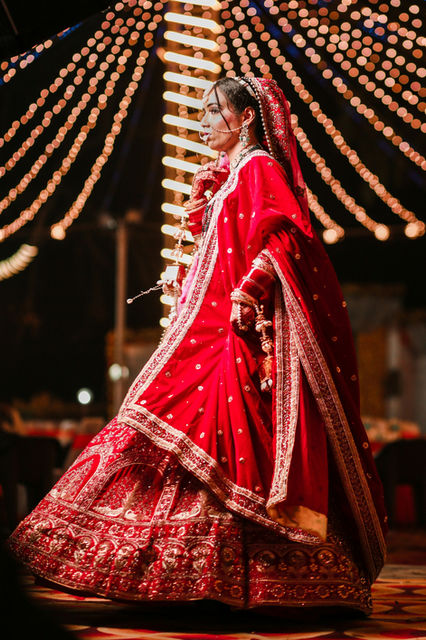 A bride in scarlet and gold beneath strings of pearls