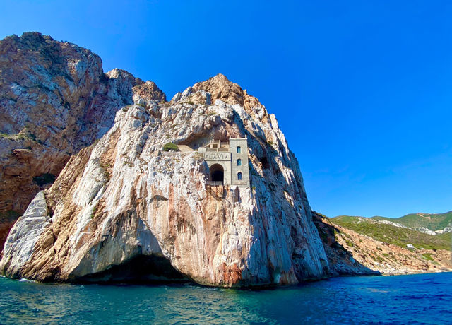 Breathtaking view of Porto Flavia built into a cliff face in Sardinia, Italy, against a clear blue sky.