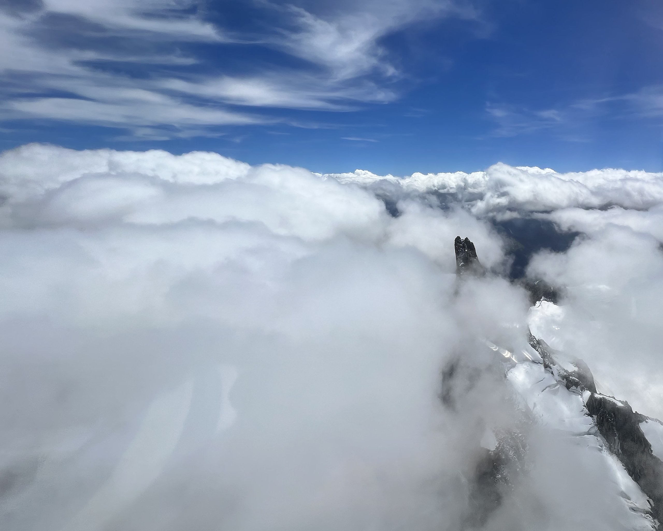 A lone rock spire breaking through a sea of cloud over the Mont Blanc massif, Chamonix